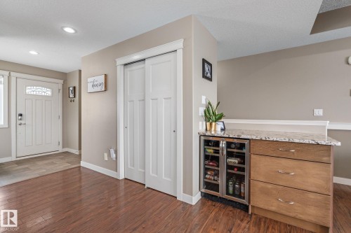 Entrance foyer with beverage cooler, dark wood-style flooring, a textured ceiling, and a dry bar - 523 55101 Ste. Anne Trail, Rural Lac Ste. Anne County, AB - Indoor Photo Showing Other Room