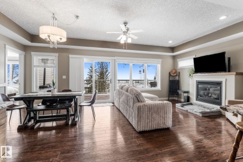 Living area featuring a textured ceiling, dark wood-type flooring, a glass covered fireplace, ceiling fan, and recessed lighting - 523 55101 Ste. Anne Trail, Rural Lac Ste. Anne County, AB - Indoor Photo Showing Living Room With Fireplace