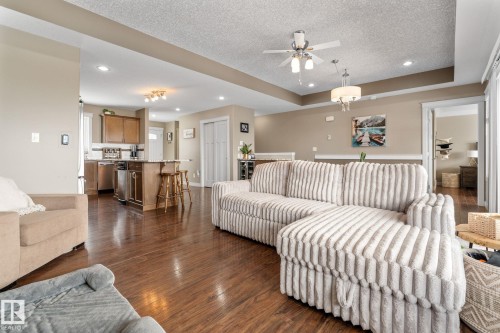Living room with a textured ceiling, dark wood-style floors, recessed lighting, ceiling fan, and a raised ceiling - 523 55101 Ste. Anne Trail, Rural Lac Ste. Anne County, AB - Indoor Photo Showing Living Room