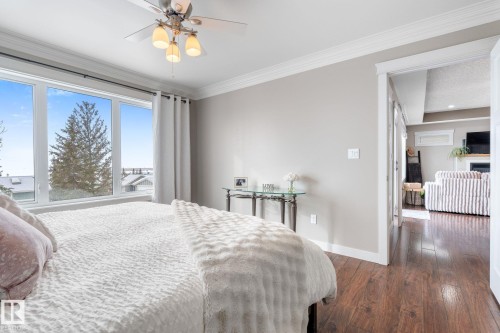 Bedroom with dark wood-style floors, ornamental molding, and a ceiling fan - 523 55101 Ste. Anne Trail, Rural Lac Ste. Anne County, AB - Indoor Photo Showing Bedroom