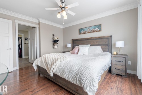 Bedroom featuring crown molding, dark wood finished floors, and a ceiling fan - 523 55101 Ste. Anne Trail, Rural Lac Ste. Anne County, AB - Indoor Photo Showing Bedroom