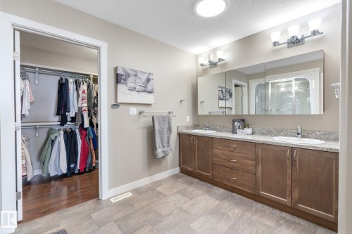 Bathroom featuring double vanity, a textured ceiling, a stall shower, a walk in closet, and light wood-style floors - 523 55101 Ste. Anne Trail, Rural Lac Ste. Anne County, AB - Indoor Photo Showing Bathroom