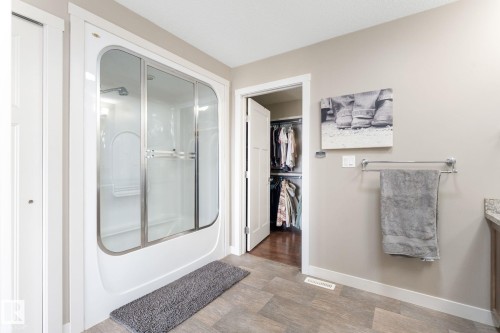 Bathroom featuring vanity, a spacious closet, light wood finished floors, and bath / shower combo with glass door - 523 55101 Ste. Anne Trail, Rural Lac Ste. Anne County, AB - Indoor Photo Showing Other Room