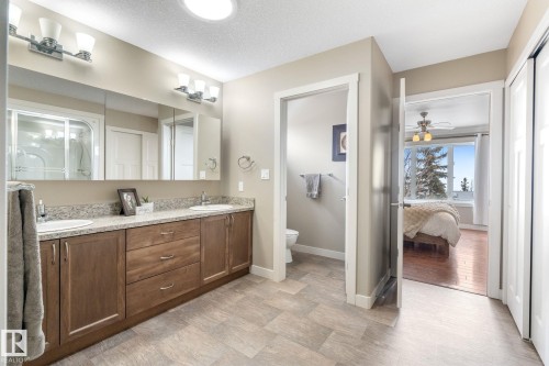 Full bath featuring double vanity, ceiling fan, connected bathroom, and a textured ceiling - 523 55101 Ste. Anne Trail, Rural Lac Ste. Anne County, AB - Indoor Photo Showing Bathroom