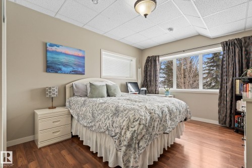 Bedroom featuring dark wood-type flooring and a drop ceiling - 523 55101 Ste. Anne Trail, Rural Lac Ste. Anne County, AB - Indoor Photo Showing Bedroom