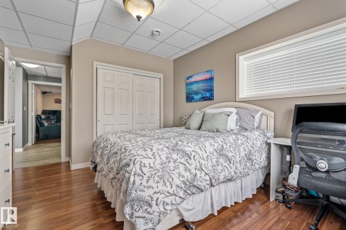 Bedroom with a paneled ceiling, a closet, dark wood finished floors, and a desk - 523 55101 Ste. Anne Trail, Rural Lac Ste. Anne County, AB - Indoor Photo Showing Bedroom