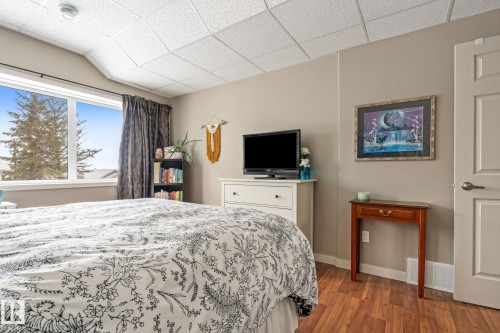 Bedroom with dark wood finished floors and a drop ceiling - 523 55101 Ste. Anne Trail, Rural Lac Ste. Anne County, AB - Indoor Photo Showing Bedroom