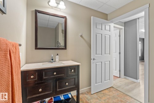 Bathroom featuring a paneled ceiling, vanity, and light stone finish flooring - 523 55101 Ste. Anne Trail, Rural Lac Ste. Anne County, AB - Indoor Photo Showing Bathroom
