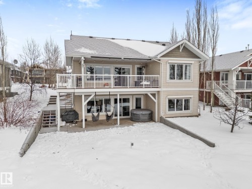 Snow covered back of property with a patio area, a wooden deck, and a hot tub - 523 55101 Ste. Anne Trail, Rural Lac Ste. Anne County, AB - Outdoor With Deck Patio Veranda With Facade