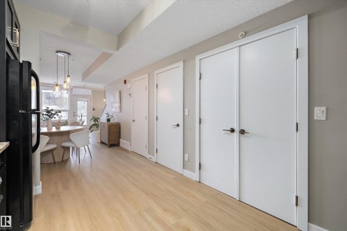 Kitchen featuring freestanding refrigerator, light wood-style flooring, decorative light fixtures, and a textured ceiling - 94 2560 Pegasus Boulevard, Edmonton, AB - Indoor Photo Showing Other Room