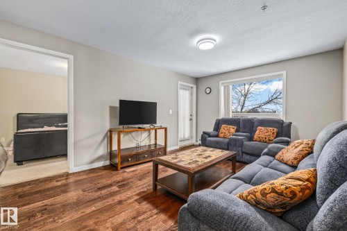 Living room featuring wood finished floors and a textured ceiling - 221 5005 165 Avenue, Edmonton, AB - Indoor Photo Showing Living Room