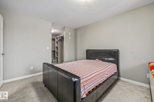 Bedroom with light colored carpet and a walk in closet - 221 5005 165 Avenue, Edmonton, AB - Indoor Photo Showing Bedroom