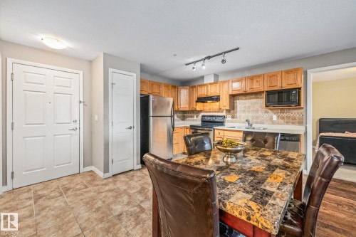 Kitchen featuring stainless steel appliances, tasteful backsplash, a kitchen breakfast bar, light countertops, and rail lighting - 221 5005 165 Avenue, Edmonton, AB - Indoor Photo Showing Kitchen