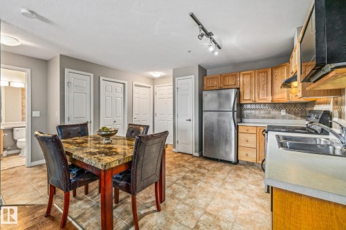 Kitchen featuring freestanding refrigerator, stove, backsplash, light countertops, and wood finish cabinets - 221 5005 165 Avenue, Edmonton, AB - Indoor