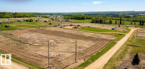 Expansive land parcel featuring cleared areas, natural grass sections, and mature tree lines in the distance - 30 River Ridge Estates, Rural Wetaskiwin County, AB 