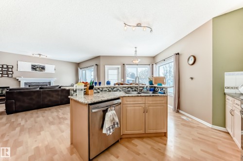 Kitchen with stainless steel dishwasher, open floor plan, an island with sink, light wood-type flooring, and track lighting - 4619 151 Avenue Nw, Edmonton, AB - Indoor Photo Showing Kitchen With Double Sink