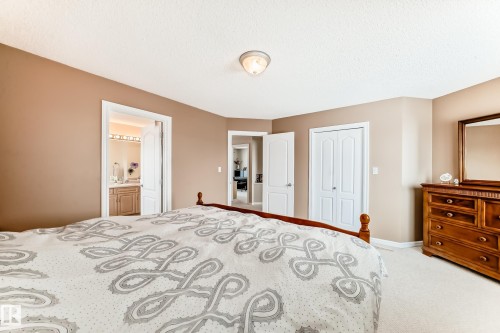 Carpeted bedroom with a closet, ensuite bath, and a textured ceiling - 4619 151 Avenue Nw, Edmonton, AB - Indoor Photo Showing Bedroom