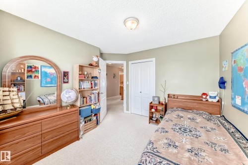 Bedroom with light colored carpet, a closet, and a textured ceiling - 4619 151 Avenue Nw, Edmonton, AB - Indoor Photo Showing Bedroom