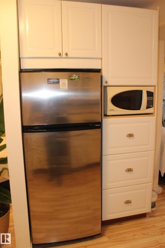 Kitchen featuring freestanding refrigerator, white microwave, light wood-style flooring, and white cabinetry - 12432 134 Street, Edmonton, AB - Indoor Photo Showing Kitchen