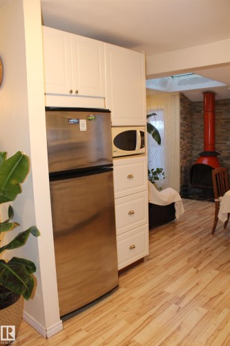 Kitchen featuring freestanding refrigerator, light wood-type flooring, white microwave, and white cabinetry - 12432 134 Street, Edmonton, AB - Indoor