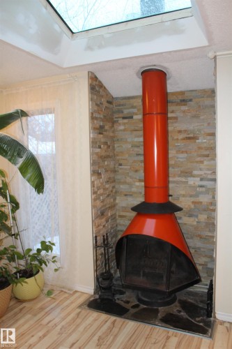 Detailed view of wood finished floors, a textured ceiling, and a wood stove - 12432 134 Street, Edmonton, AB - Indoor With Fireplace