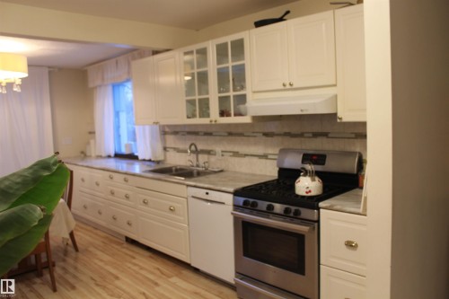 Kitchen with gas range, white cabinets, light countertops, glass insert cabinets, and white dishwasher - 12432 134 Street, Edmonton, AB - Indoor Photo Showing Kitchen With Double Sink