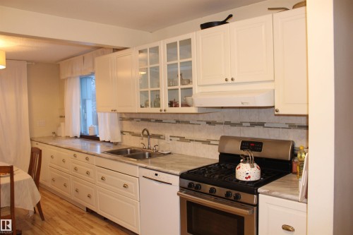 Kitchen featuring stainless steel range with gas cooktop, glass fronted cabinets, light countertops, dishwasher, and white cabinets - 12432 134 Street, Edmonton, AB - Indoor Photo Showing Kitchen With Double Sink