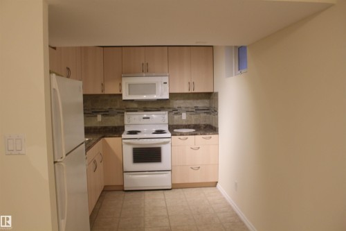 Kitchen with white appliances, light wood finish cabinets, tasteful backsplash, and dark stone countertops - 12432 134 Street, Edmonton, AB - Indoor Photo Showing Kitchen