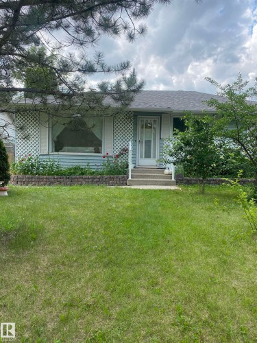 View of front of property featuring a front yard, covered porch, a shingled roof, and brick siding - 12432 134 Street, Edmonton, AB - Outdoor