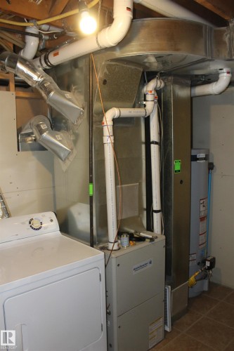 Laundry area featuring washer / clothes dryer, dark tile patterned floors, water heater, and heating unit - 12432 134 Street, Edmonton, AB - Indoor
