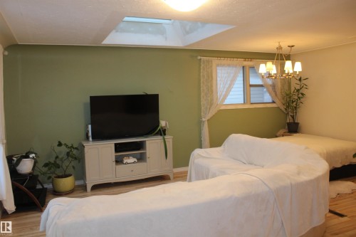 Living area with wood finished floors, suspended lighting, and a textured ceiling - 12432 134 Street, Edmonton, AB - Indoor Photo Showing Other Room