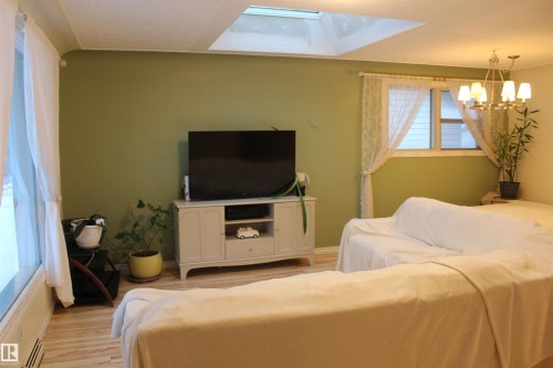 Living room with wood finished floors, suspended lighting, and a baseboard radiator - 12432 134 Street, Edmonton, AB - Indoor Photo Showing Bedroom