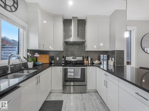 Kitchen featuring dark stone counters, stainless steel appliances, white cabinets, and decorative backsplash - 3510 48 Avenue, Beaumont, AB - Indoor Photo Showing Kitchen With Double Sink With Upgraded Kitchen