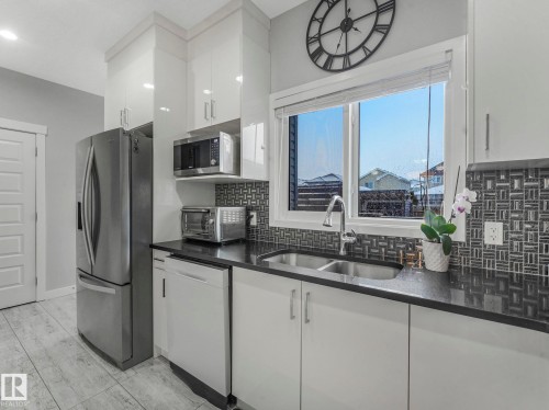 Kitchen with stainless steel appliances, white cabinetry, dark stone counters, tasteful backsplash, and modern cabinets - 3510 48 Avenue, Beaumont, AB - Indoor Photo Showing Kitchen With Double Sink