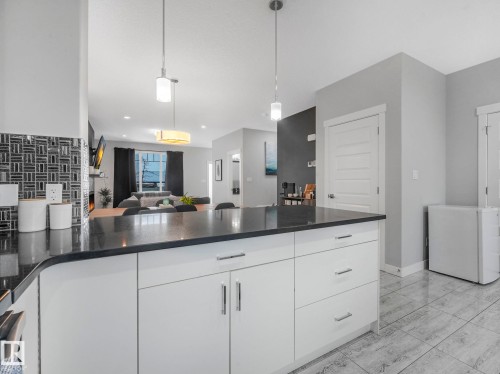 Kitchen featuring open floor plan, white cabinetry, white refrigerator, hanging light fixtures, and dark stone counters - 3510 48 Avenue, Beaumont, AB - Indoor Photo Showing Kitchen