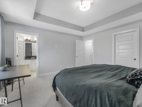 Bedroom with light colored carpet, a textured ceiling, and ensuite bathroom - 3510 48 Avenue, Beaumont, AB - Indoor Photo Showing Bedroom