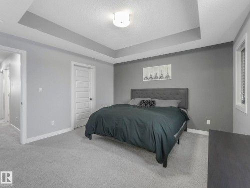 Bedroom with a tray ceiling, light carpet, and a textured ceiling - 3510 48 Avenue, Beaumont, AB - Indoor Photo Showing Bedroom