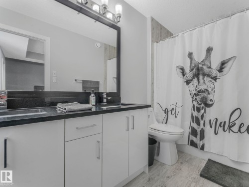 Full bath with double vanity, a textured ceiling, and shower / bathtub combination with curtain - 3510 48 Avenue, Beaumont, AB - Indoor Photo Showing Bathroom