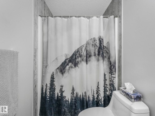 Bathroom featuring a shower with shower curtain, a mountain view, and a textured ceiling - 3510 48 Avenue, Beaumont, AB - Indoor Photo Showing Bathroom