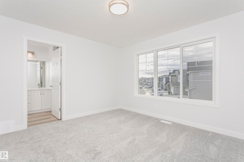 Unfurnished bedroom with light carpet, ensuite bathroom, and a textured ceiling - 9564 Carson Bend, Edmonton, AB - Indoor Photo Showing Other Room