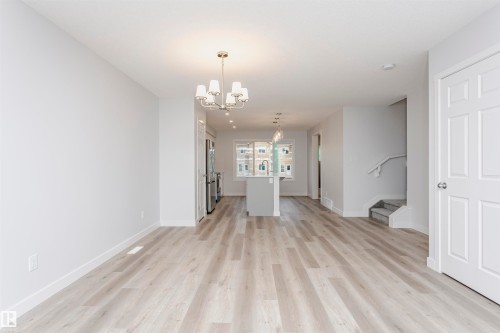 Unfurnished living room with light wood-style flooring and a chandelier - 9564 Carson Bend, Edmonton, AB - Indoor Photo Showing Other Room