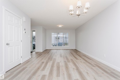 Unfurnished living room featuring light wood-type flooring and suspended lighting - 9564 Carson Bend, Edmonton, AB - Indoor Photo Showing Other Room