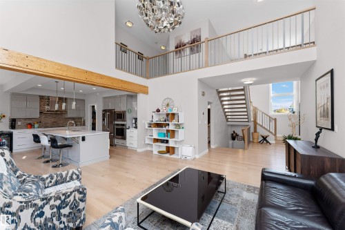 Living room featuring light wood-style floors, suspended lighting, and a high ceiling - 7404 May Common, Edmonton, AB - Indoor Photo Showing Other Room