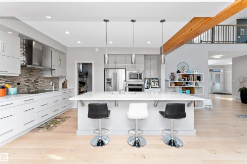 Kitchen featuring gray cabinets, light wood-style floors, a kitchen breakfast bar, and stainless steel appliances - 7404 May Common, Edmonton, AB - Indoor Photo Showing Kitchen With Upgraded Kitchen