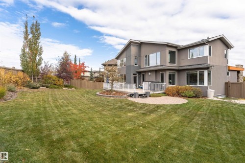 Rear view of house featuring a wooden deck, stucco siding, and a fenced backyard - 7404 May Common, Edmonton, AB - Outdoor With Deck Patio Veranda