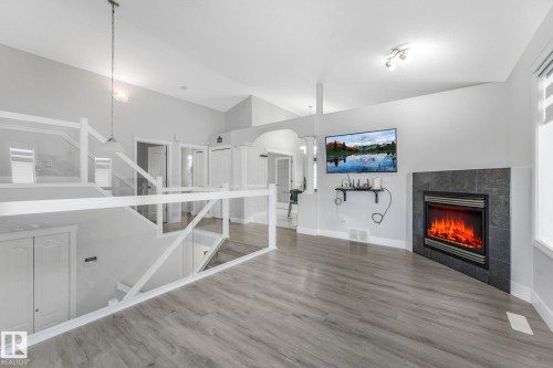 Unfurnished living room featuring a fireplace, arched walkways, and wood finished floors - 2919 151A Avenue, Edmonton, AB - Indoor With Fireplace