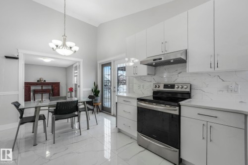 Kitchen with stainless steel electric range, white cabinets, light stone countertops, and vaulted ceiling - 2919 151A Avenue, Edmonton, AB - Indoor Photo Showing Kitchen With Upgraded Kitchen