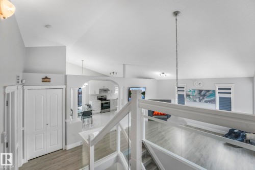 Hall featuring lofted ceiling, an upstairs landing, arched walkways, and light wood-style flooring - 2919 151A Avenue, Edmonton, AB - Indoor
