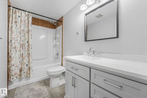 Bathroom featuring vanity, shower / bath combination with curtain, and light wood-style floors - 2919 151A Avenue, Edmonton, AB - Indoor Photo Showing Bathroom