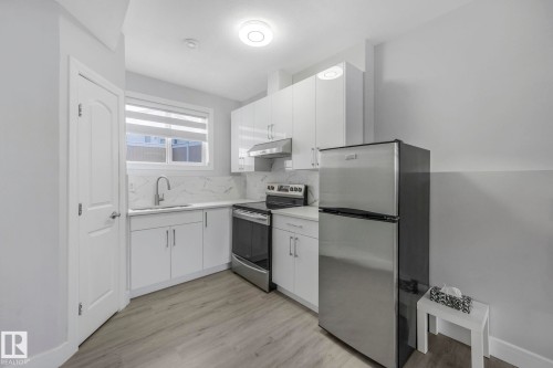 Kitchen with stainless steel appliances, white cabinetry, light wood-style floors, tasteful backsplash, and modern cabinets - 2919 151A Avenue, Edmonton, AB - Indoor Photo Showing Kitchen With Upgraded Kitchen
